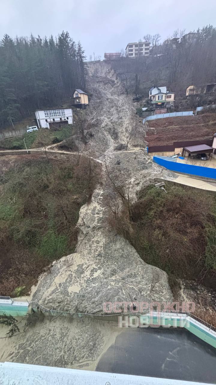 Сочи столкнулся с серьезными транспортными проблемами из-за повторных сходов селя в районе улицы Тепличной. По данным жителей ЖК «Министерские озёра», оползень происходил уже трижды с начала 2026 года, что привело к затоплению дорог и образованию пробок протяженностью до 10 километров. Общественный транспорт в районе ходит с перебоями — интервал между рейсами составляет полтора часа. В зоне риска находятся жилые дома и гимназия, куда привозят детей из соседних районов. Жители сообщают о размытой почве и дестабилизации склона, что создает угрозу обрушения зданий. Местные жители направили более 50 заявлений в администрацию города. Чиновники, по их словам, ограничились съемкой видео и публикацией отчетов в соцсетях, но реальные меры по устранению последствий оползня не были приняты. Ранее, в конце 2024 года, аварийные службы уже вывозили грунт и устанавливали металлические блоки, однако ситуация остается критической. Жители требуют введения режима повышенной готовности и принятия срочных мер по отводу селя для предотвращения дальнейших разрушений.. Сочи, селевые потоки, транспортный коллапс, ЖК Министерские озёра, ЧП