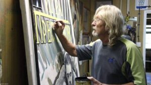 Василий Чеботарёв, легендарный художник киноафиш в советском стиле, временно уходит из профессии. 🎨 Причина — проблемы со здоровьем. По данным Mash, 66-летний мастер из Камышина Волгоградской области перенёс операцию на сосуды и сейчас восстанавливается. Местные СМИ ранее писали, что Чеботарёва якобы уволили из-за финансовых трудностей кинотеатра «Дружба» и перехода на современные афиши. Однако сам художник не исключает возвращения к работе, когда позволит самочувствие. За годы творчества Чеботарёв создал более 700 плакатов, превратив Камышин в место паломничества для ценителей ручной работы. На одну афишу у него уходило до трёх дней. К сожалению, он не успел завершить плакаты к новым фильмам, включая «Аватар: Пламя и пепел» и «Возвращение в Сайлент Хилл». 🎬 Пожелаем мастеру скорейшего выздоровления! 💪. Василий Чеботарёв, киноафиши, Камышин, советский стиль, здоровье